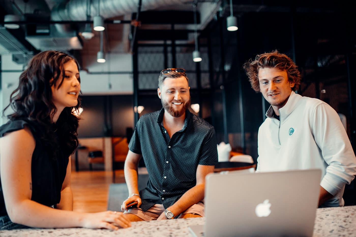 Three colleagues gathered around a laptop